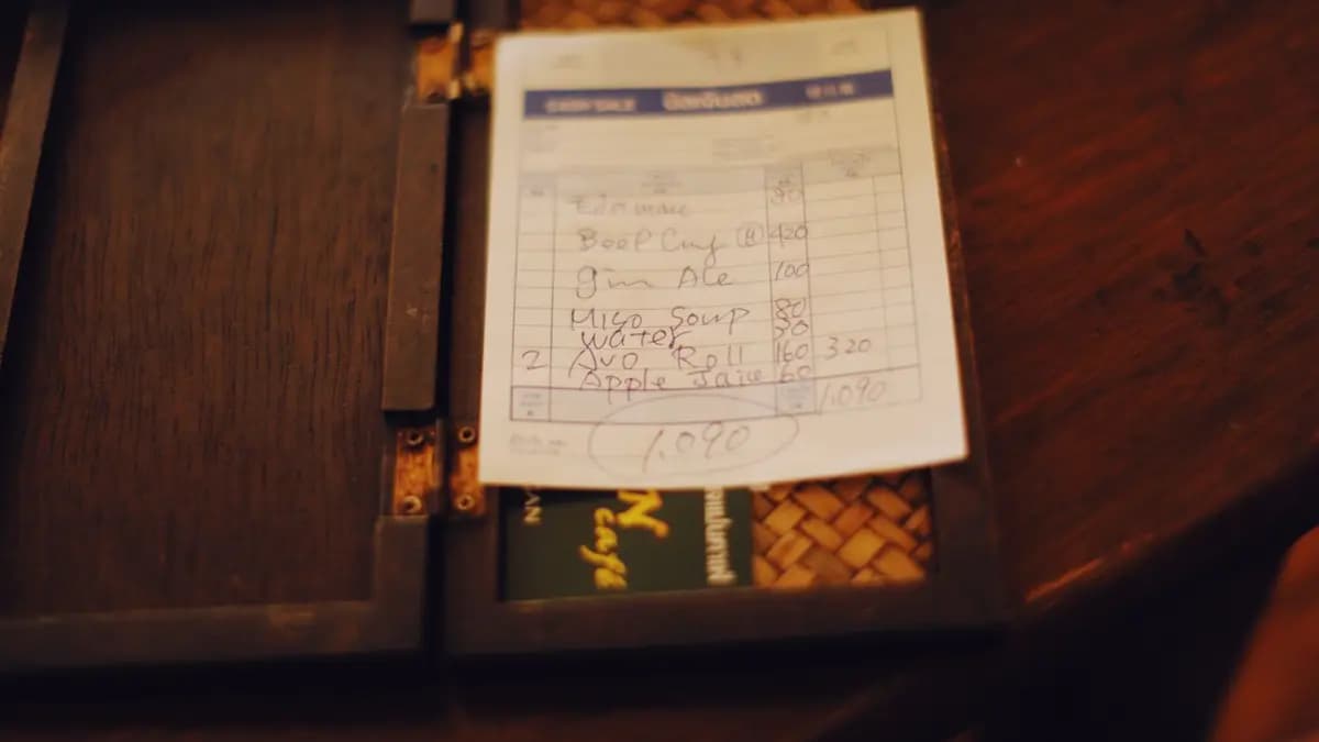 Client care fotografiază bonul fiscal cu telefonul în fața casei de marcat dintr-un magazin de cartier
