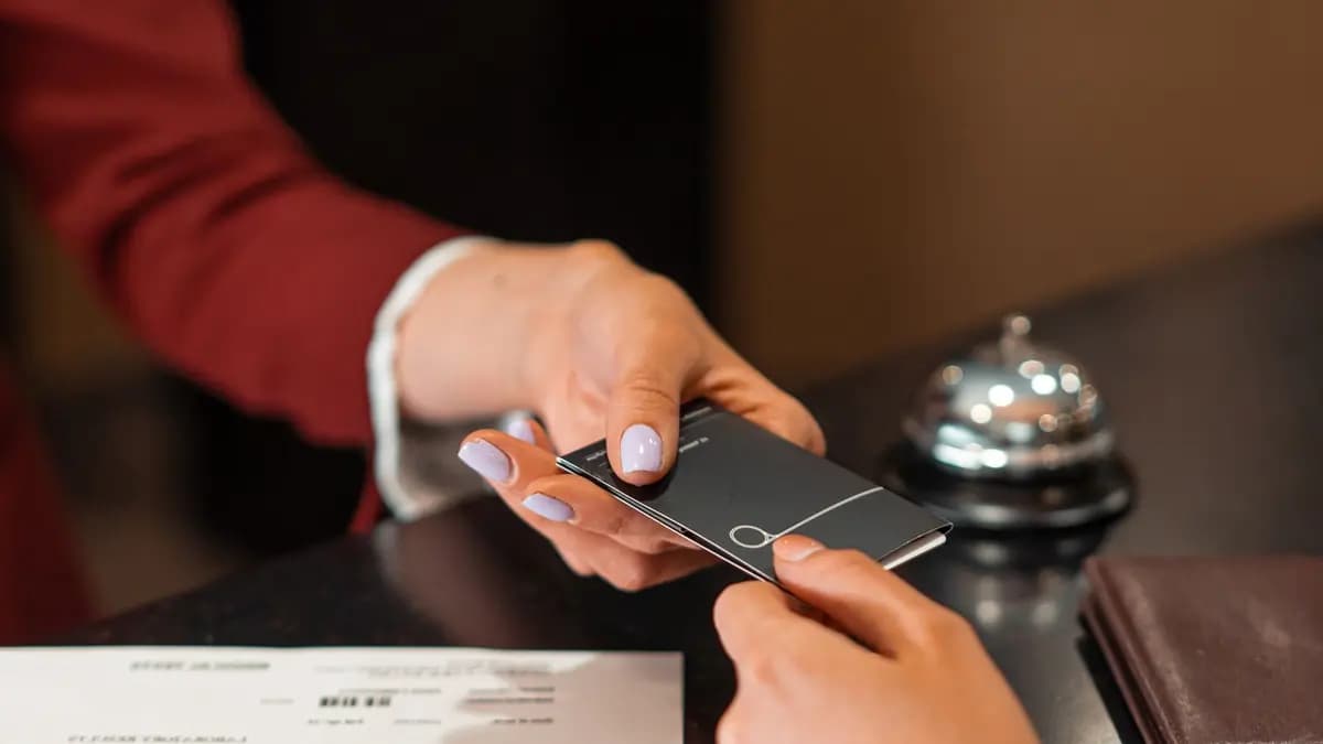 Client care ține telefonul cu cardul de fidelitate digital deschis în aplicație, la casa unui magazin de cartier
